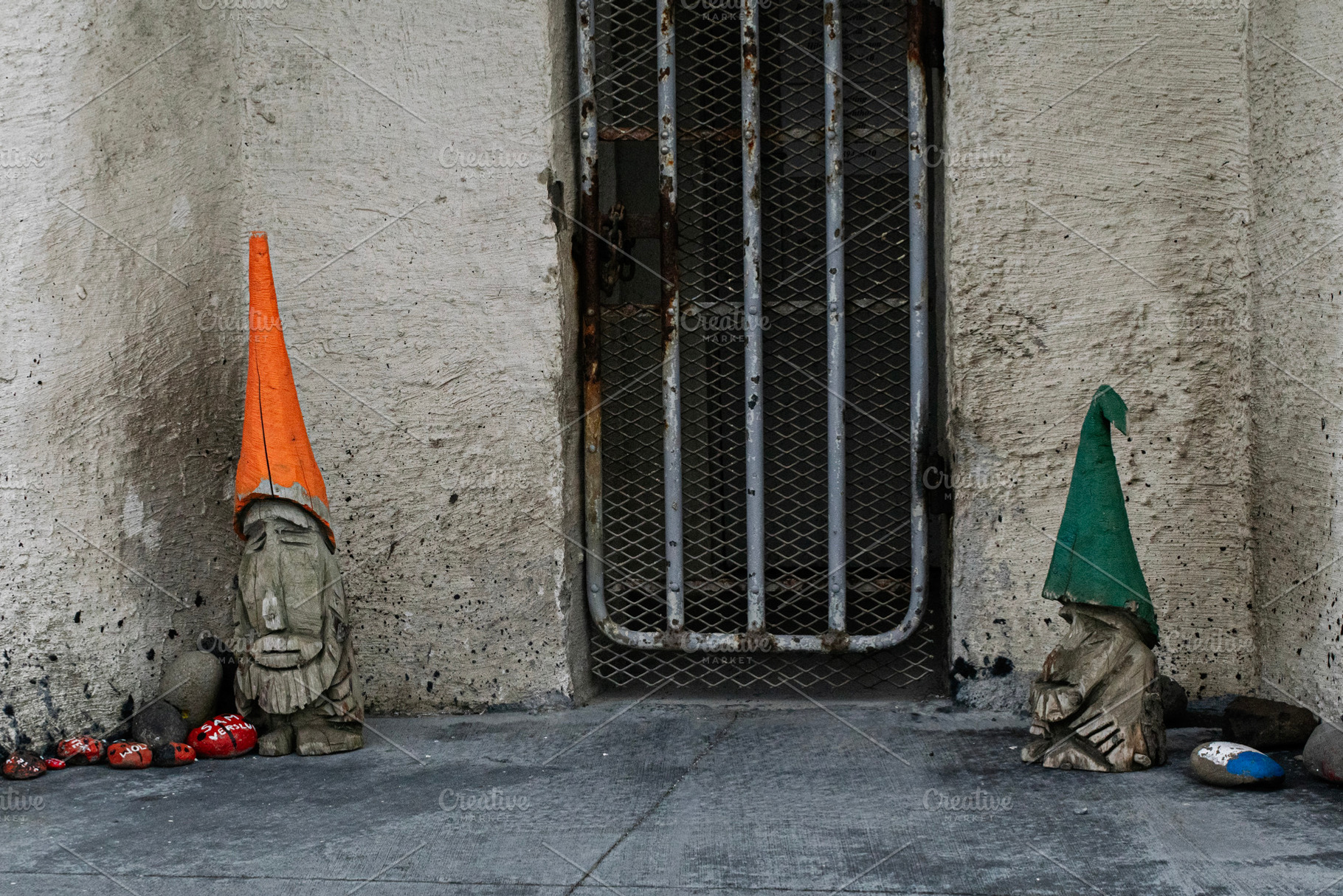 Two carved gnomes outside a wall in Akranes, Iceland near a gate, a Photo by AS photostudio