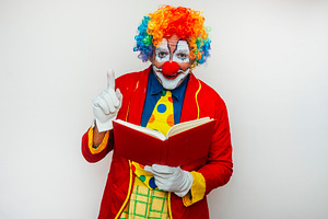 Happy smiling clown reading a book, a Person Photo by karrastock