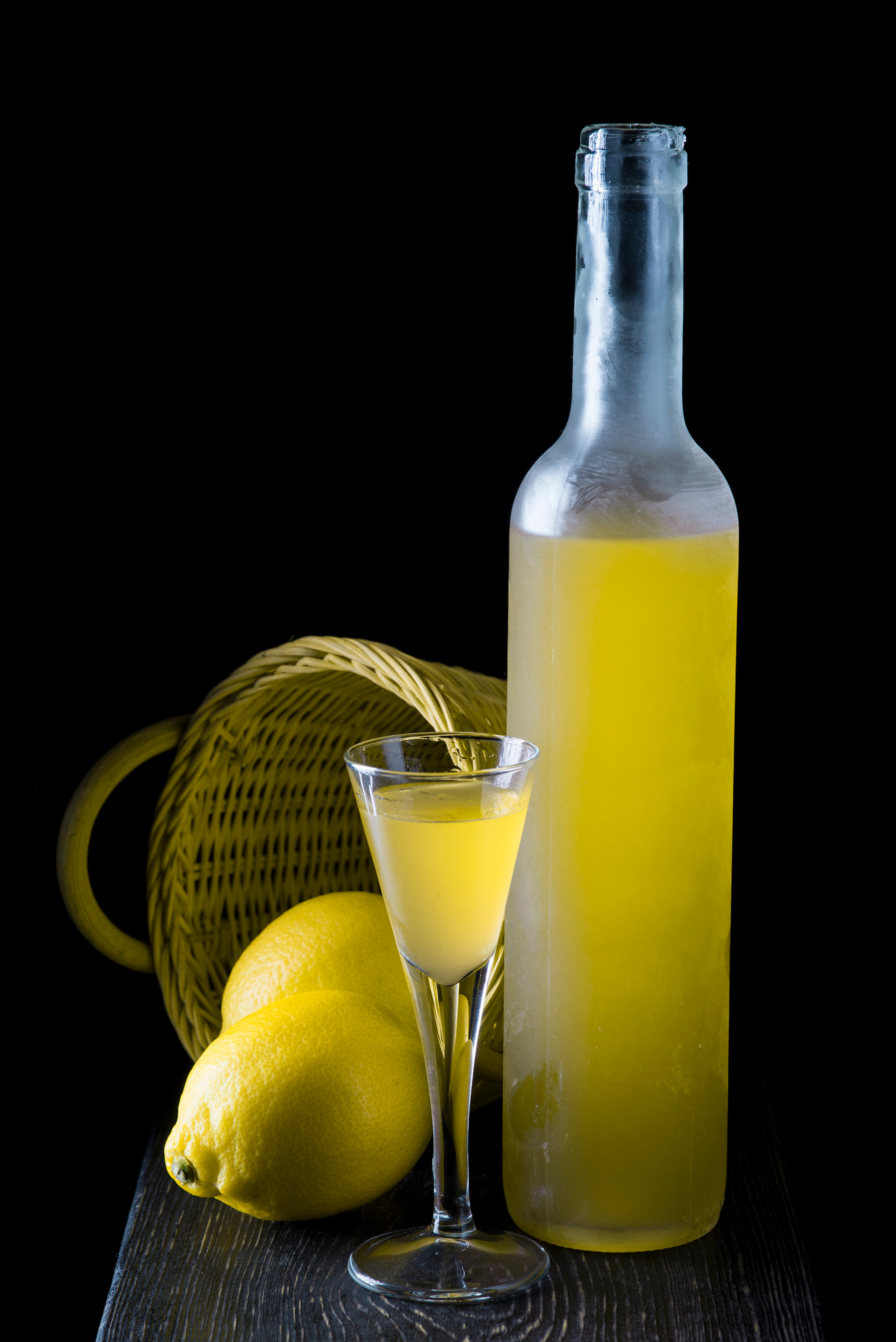Italian limoncello in a shot glass on a black wooden background containing, a Food & Drink Photo by Angel Simon Photography