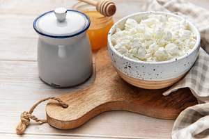 Cottage cheese in bowl with honey and sugar pot, a Food & Drink Photo by Olena Rudo