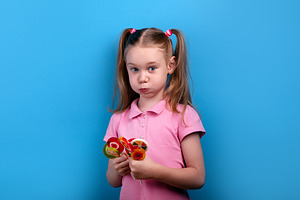 Cute girl in a pink shirt puffing her cheeks while holding colo, a Person Photo by Ales Munt