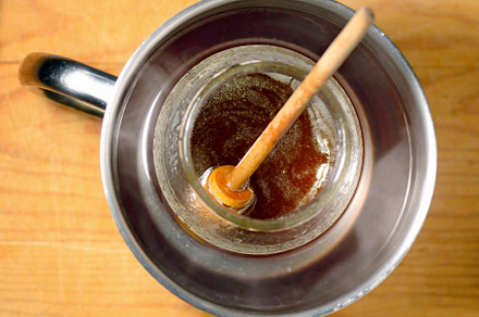 honey glass  jar  mixed on a metalllic  pot with hot water with