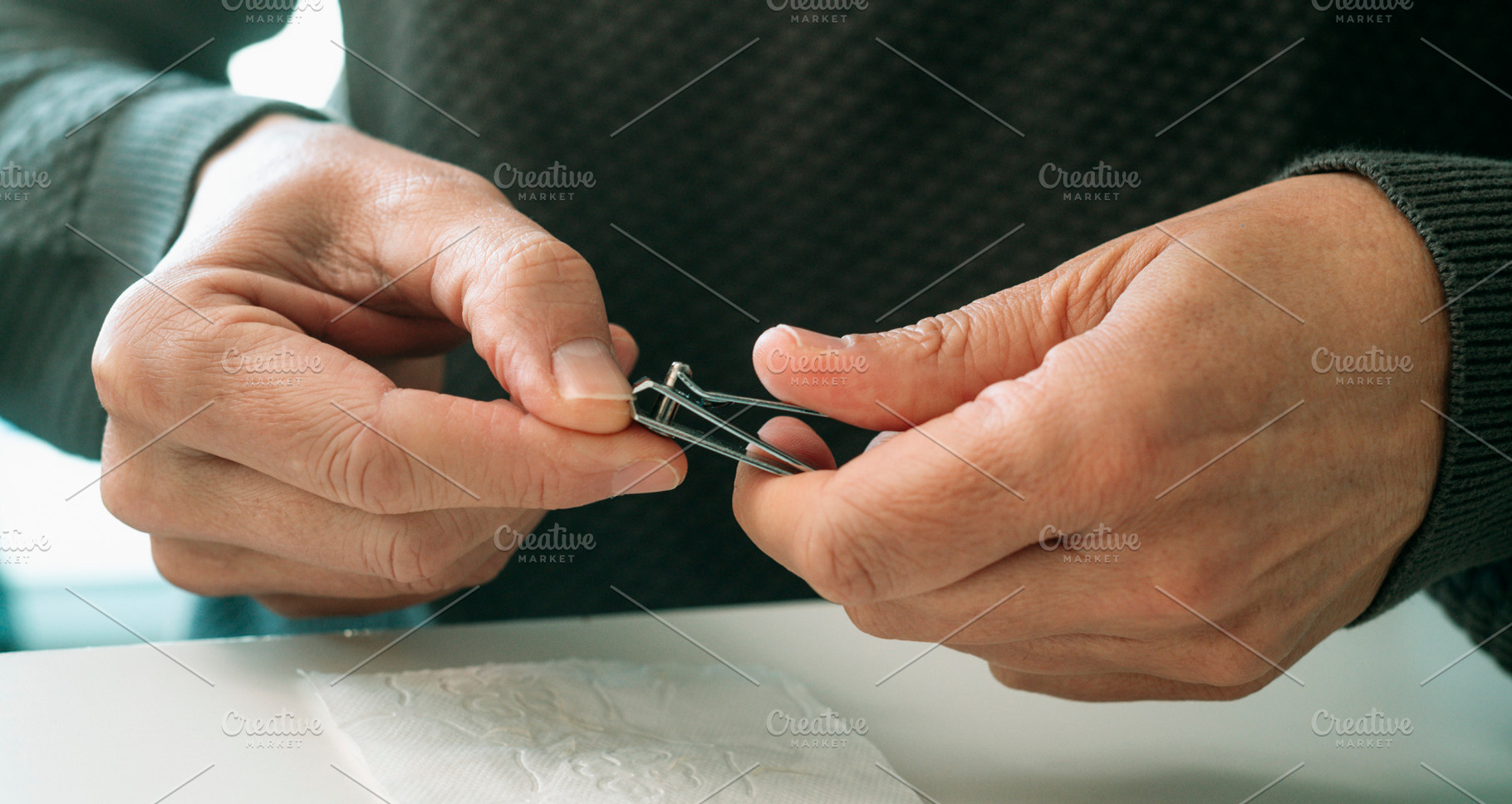 a man trims his thumb nail with precision, a Photo by Nito