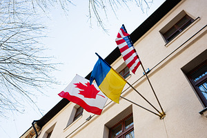 Flags of Canada, USA, and Ukraine displayed outside on a clear sunny day, a Photo by AS photostudio