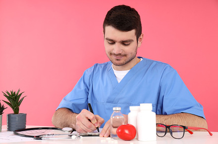 Doctor intern sits at workplace on pink background, a Person Photo by AtlasStudio PRO