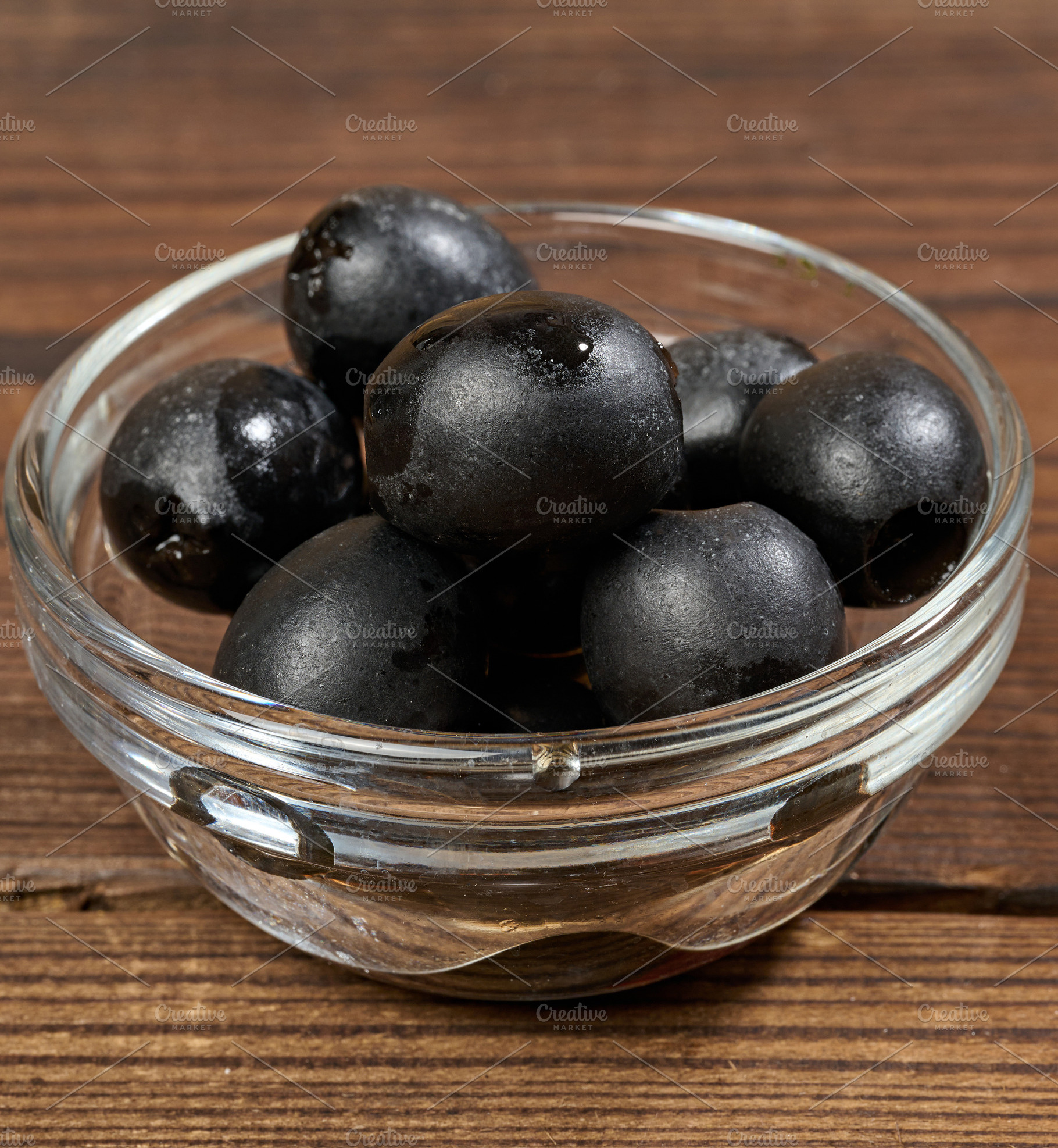 Pitted olives in a glass bowl on a wooden table, a Food & Drink Photo by ndanko