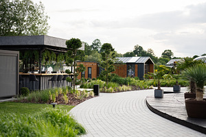 Modern outdoor bar with stylish seating amidst scenic greenery and small buildi, a Photo by AS photostudio