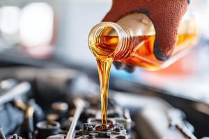 Pouring engine oil into a car engine during routine maintenance at a garage, a Photo by AlyaAnd