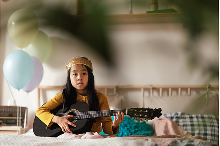 Happy girl playing on the guitar in, a School & Education Photo by HalfPoint
