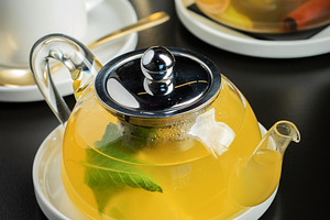 Fruit tea with mango and mint in a glass teapot on the table, a Food & Drink Photo by Budarinphoto