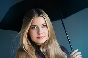 Blonde woman holding a black umbrella, looking directly forward., a Person Photo by Studio ANNA