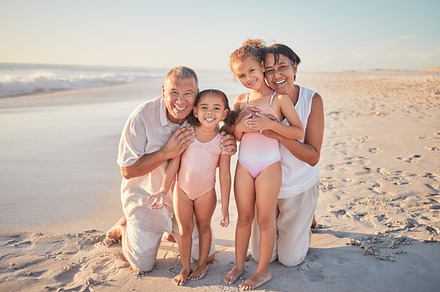 Grandparents with children, happy on beach on holiday and enjoying retirement. Grandpa, grandma and kids enjoy  afternoon playing in ocean summer sun.  Family love time together, by the sea and sand, a Photo by Peopleimages.com