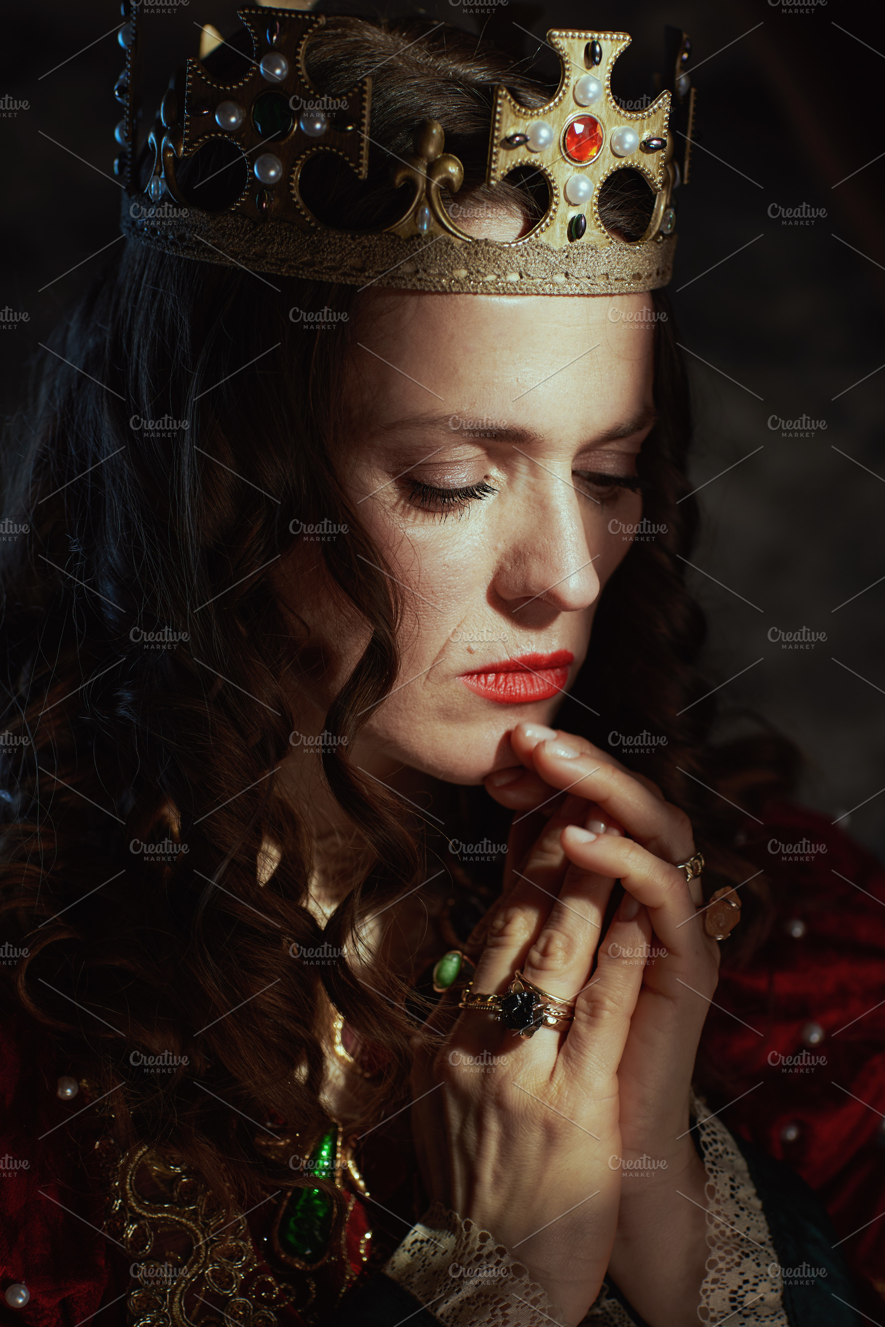 medieval queen in red dress with crown praying, a Person Photo by Alliance Images