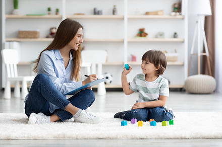 Cute little boy playing with colorful blocks, young professional woman psycholo, a Photo by Prostock-Studio