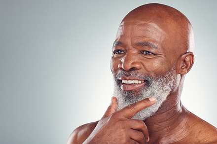 Senior black man, smile and beard in skincare for facial treatment, cosmetics or thinking on mockup. Happy elderly African American male smiling face in satisfaction against a grey studio background, a Photo by Peopleimages.com
