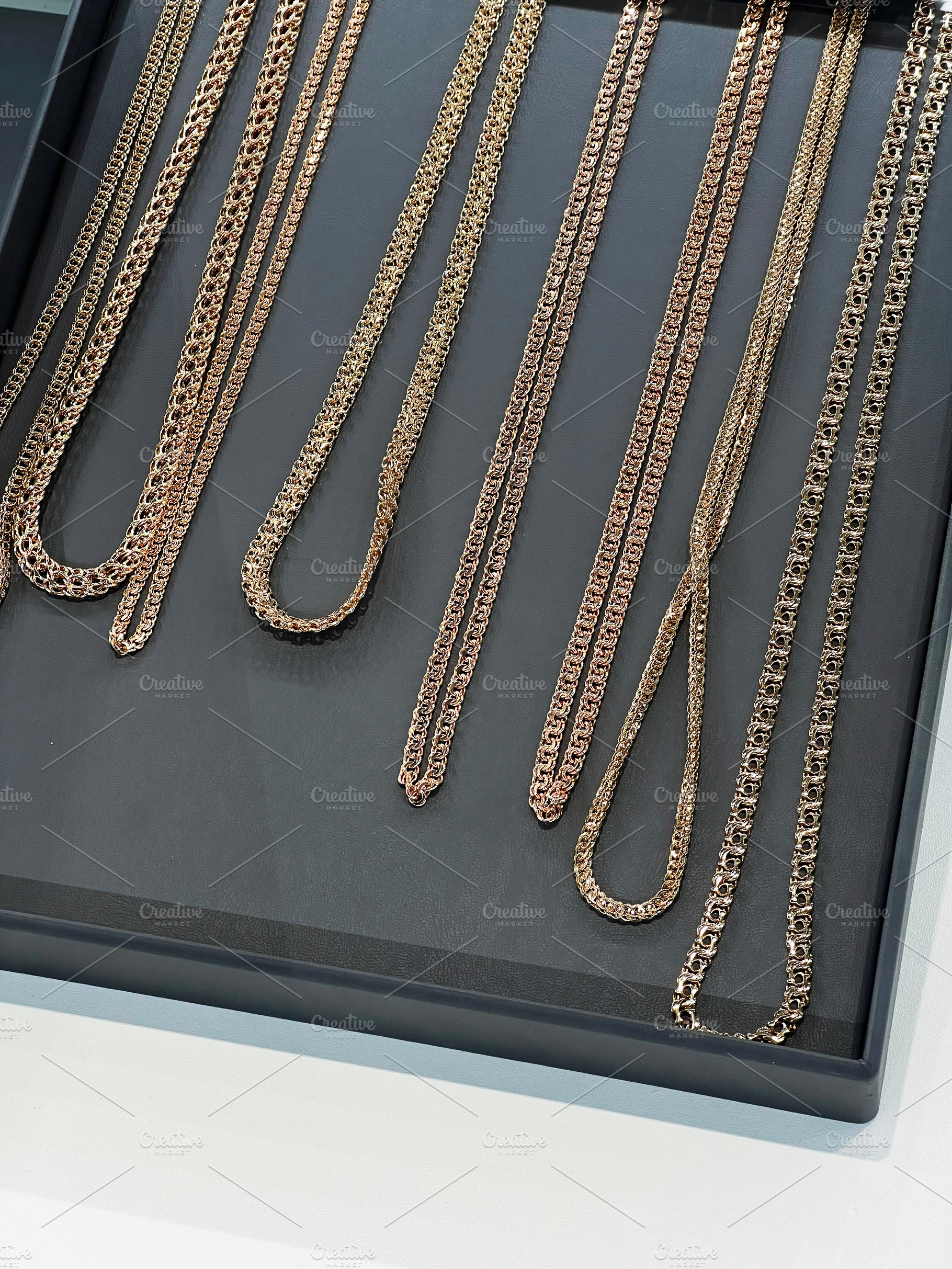 Elegant collection of gold chain necklaces displayed on a luxury black tray, a Photo by AS photostudio
