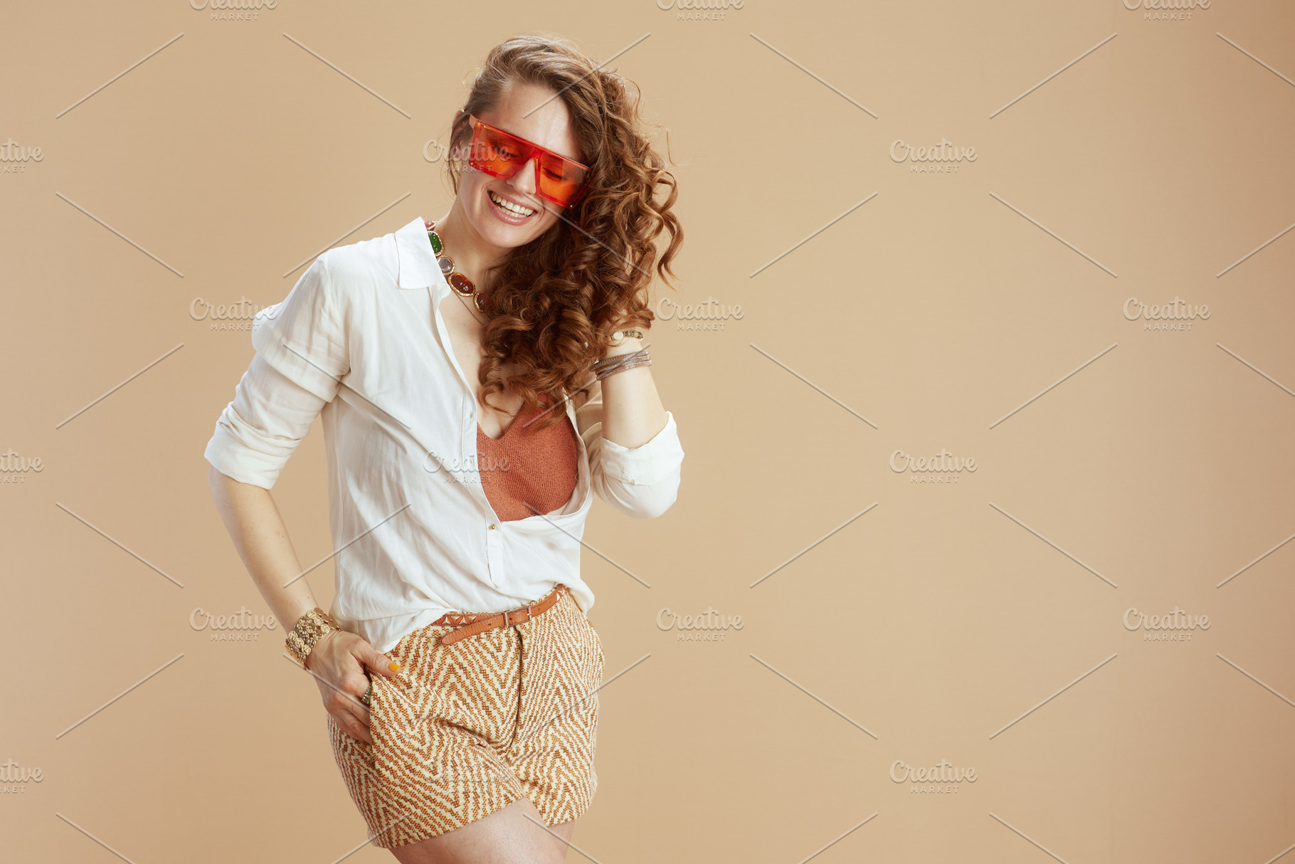smiling trendy woman in blouse and shorts on beige, a Person Photo by Alliance Images