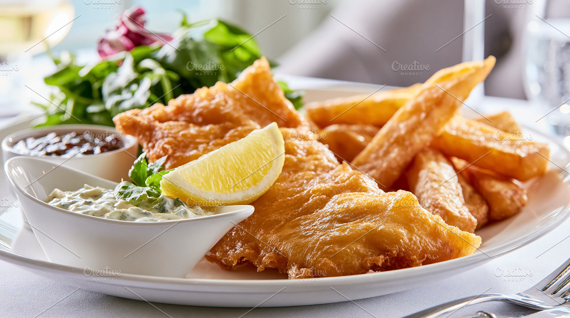 Crispy golden fish and chips served on a white plate with fresh salad greens, l, a Photo by Studio ANNA