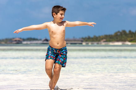 Funny kid running throw the water of a beach with open arms, a Person Photo by Cosca