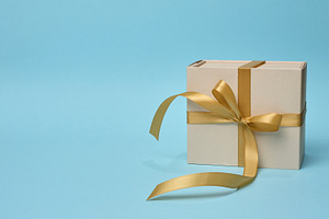 Gift box with a golden silk bow on a blue background, a Holiday Photo by ndanko