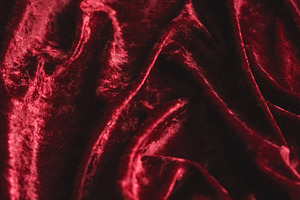 Rich red velvet fabric creating soft, flowing drapes and luxurious texture back, a Photo by Studio ANNA