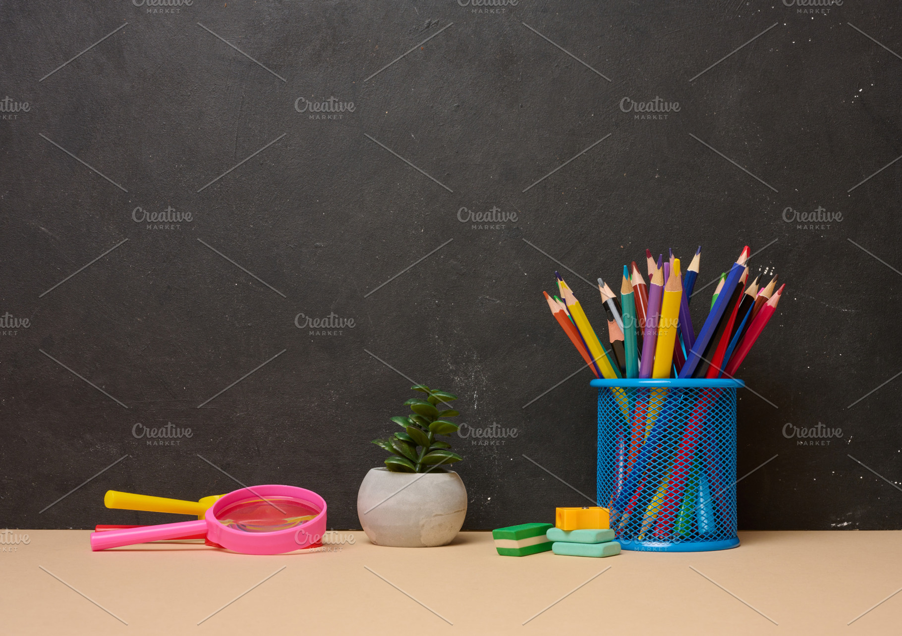 Multicolored pencils in a blue glass, a pink magnifying glass, e, a School & Education Photo by ndanko