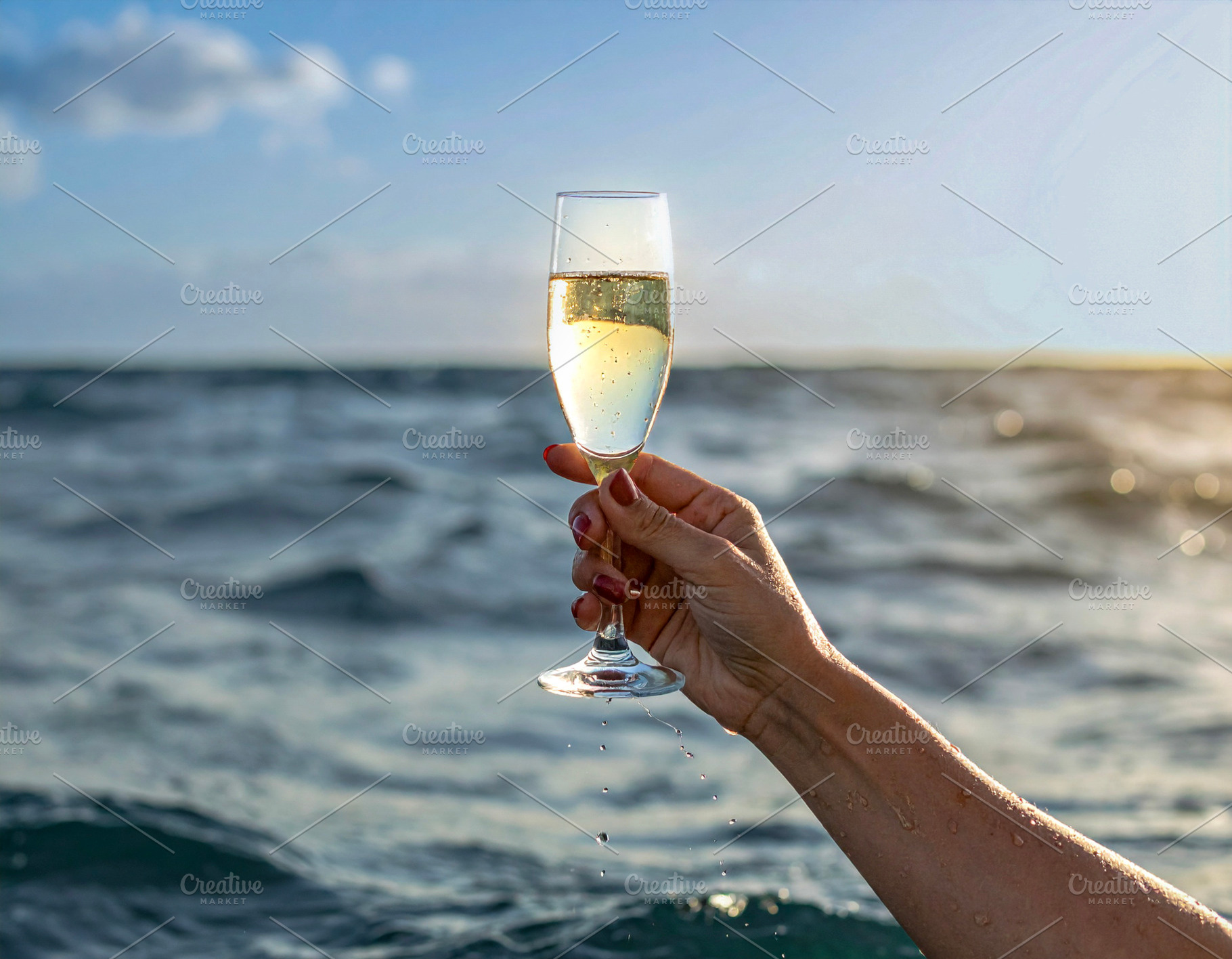 Arm raising a champagne glass from the middle of the sea, a Food & Drink Photo by DanFLCreativo