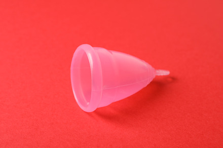 Menstrual cup on red background, close up, a Health & Medical Photo by AtlasStudio