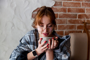 Woman in glasses wrapped in blanket enjoying hot drink indoors, a Person Photo by Photostock