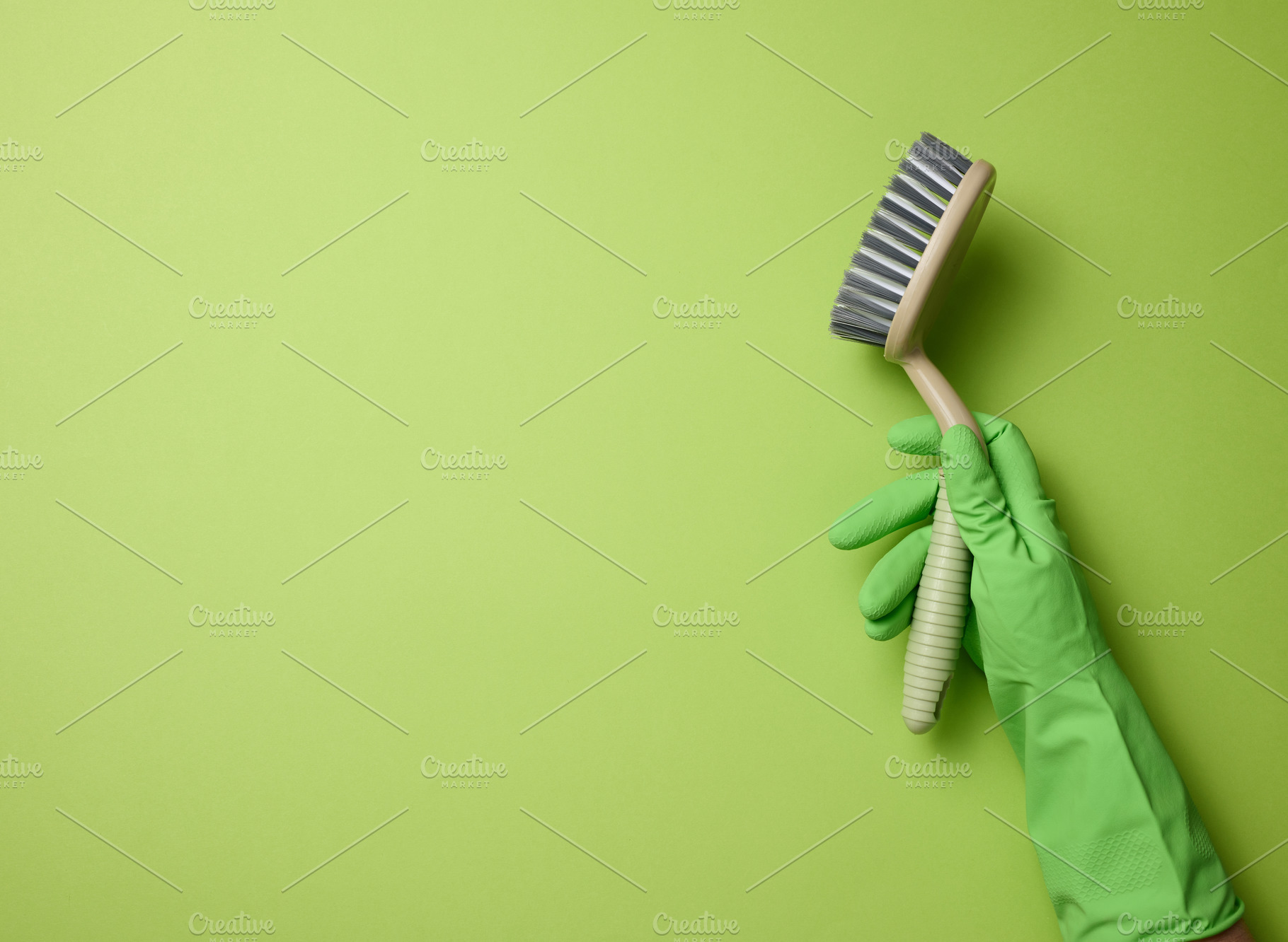 hand in a green rubber glove holds a plastic cleaning brush on a, a Photo by ndanko