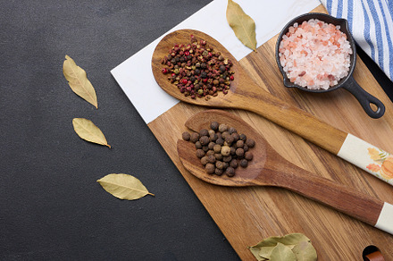 Peppercorns and salt in a wooden spoon on a black table, top vie, a Food & Drink Photo by ndanko