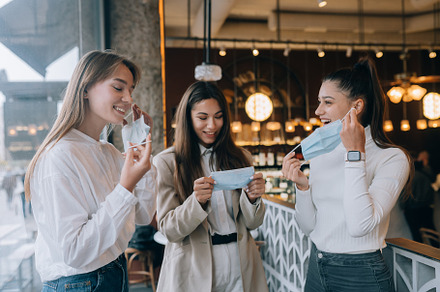 Caucasian women taking off a medical mask in a cafe