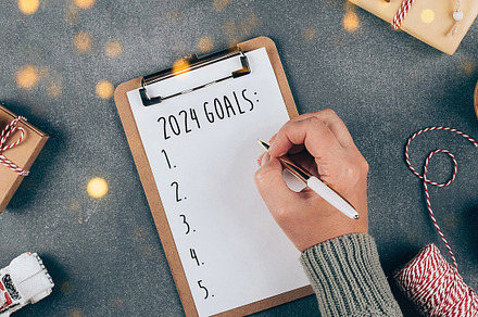 Woman's hand writing 2024 Goals in notebook. Top view, flat lay. Banner, a Holiday Photo by Anikona