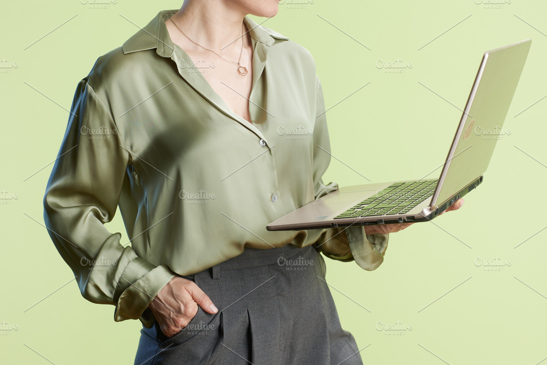 Professional woman with laptop on green background, a Person Photo by Alliance Images