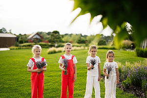 Four young girls holding lavender flowers in a lush outdoor garden setting, a Photo by AS photostudio