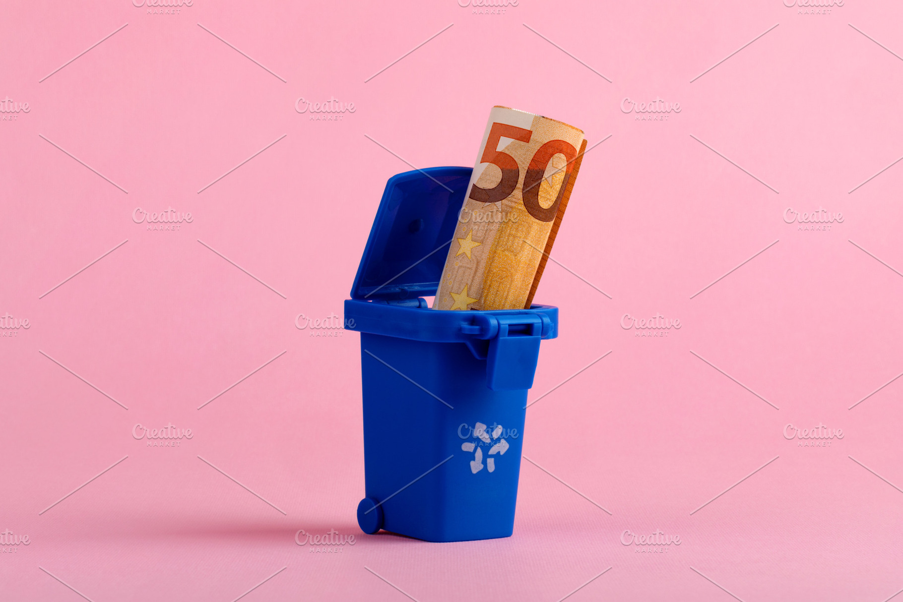 Fifty euro banknote in blue trash bin on pink background, symbolizing financial, a Business Photo by Ales Munt