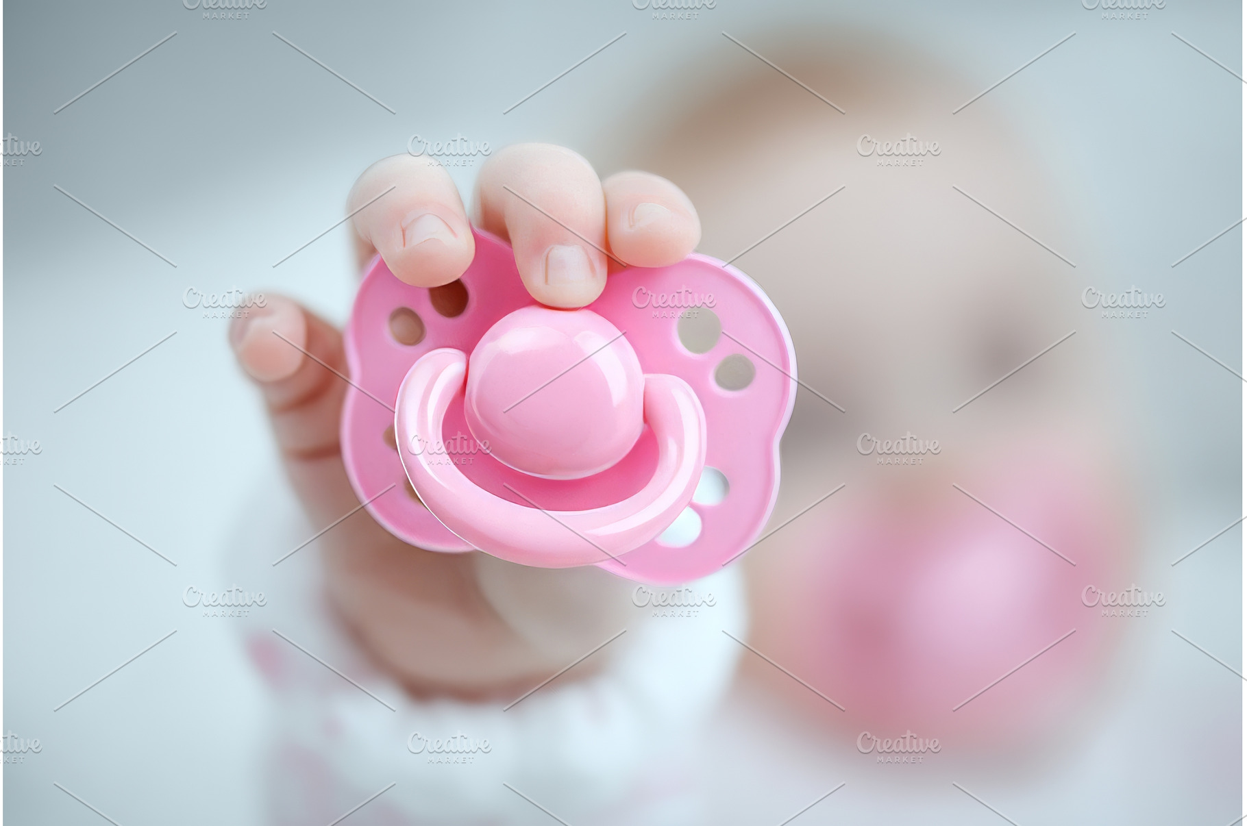 A pacifier is held by baby hands, a Person Photo by ZinetroN
