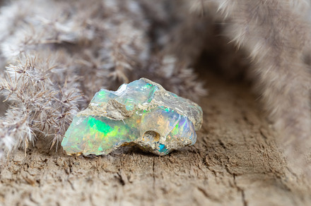 Colorful boulder opal stone on wood, a Nature Photo by Andriana Syvanych