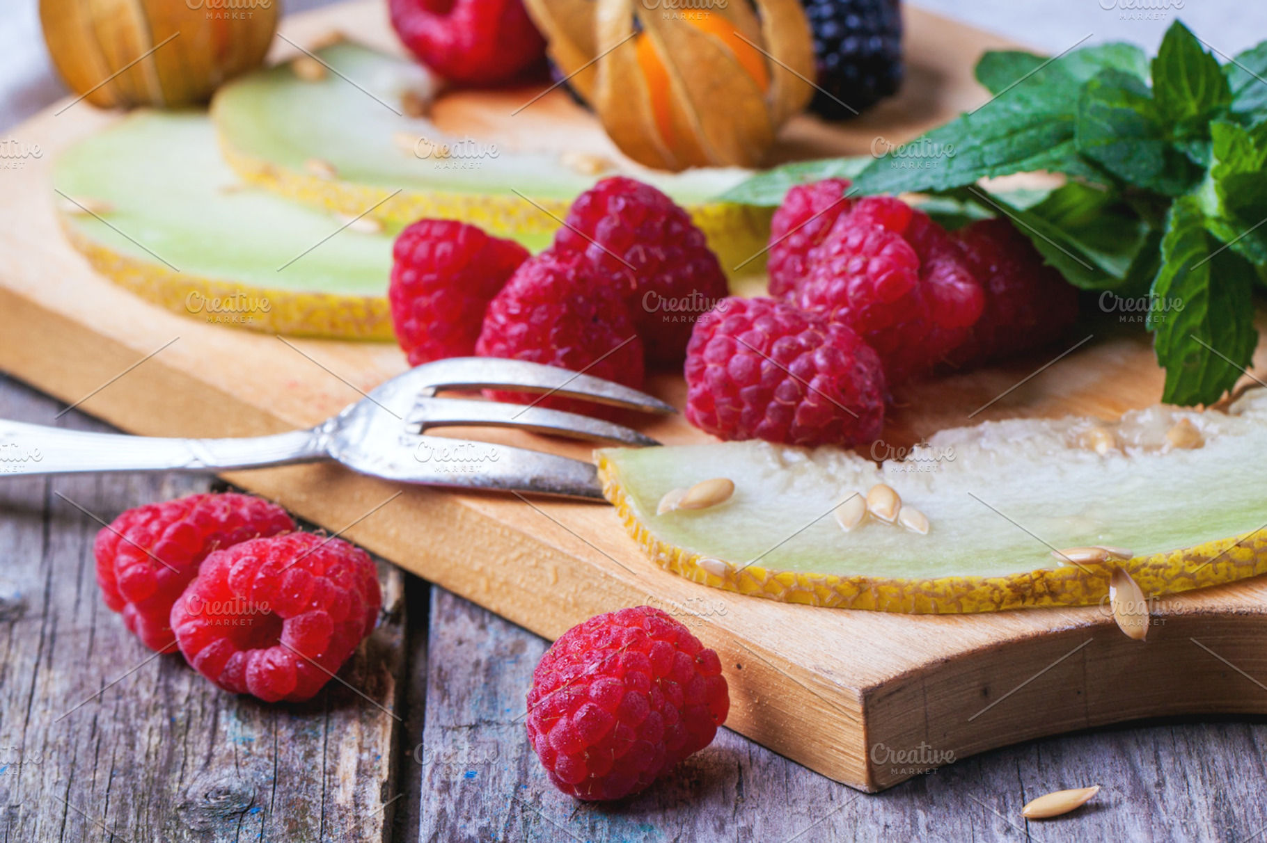 Berries mint and melon on wooden cutting board stock photo containing berries