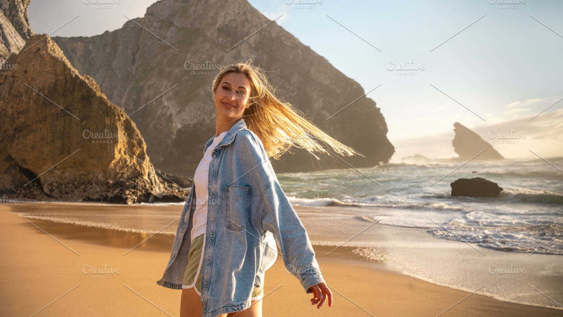 Smiling woman standing against huge rock on seashore at beach, a Photo by andreonegin market
