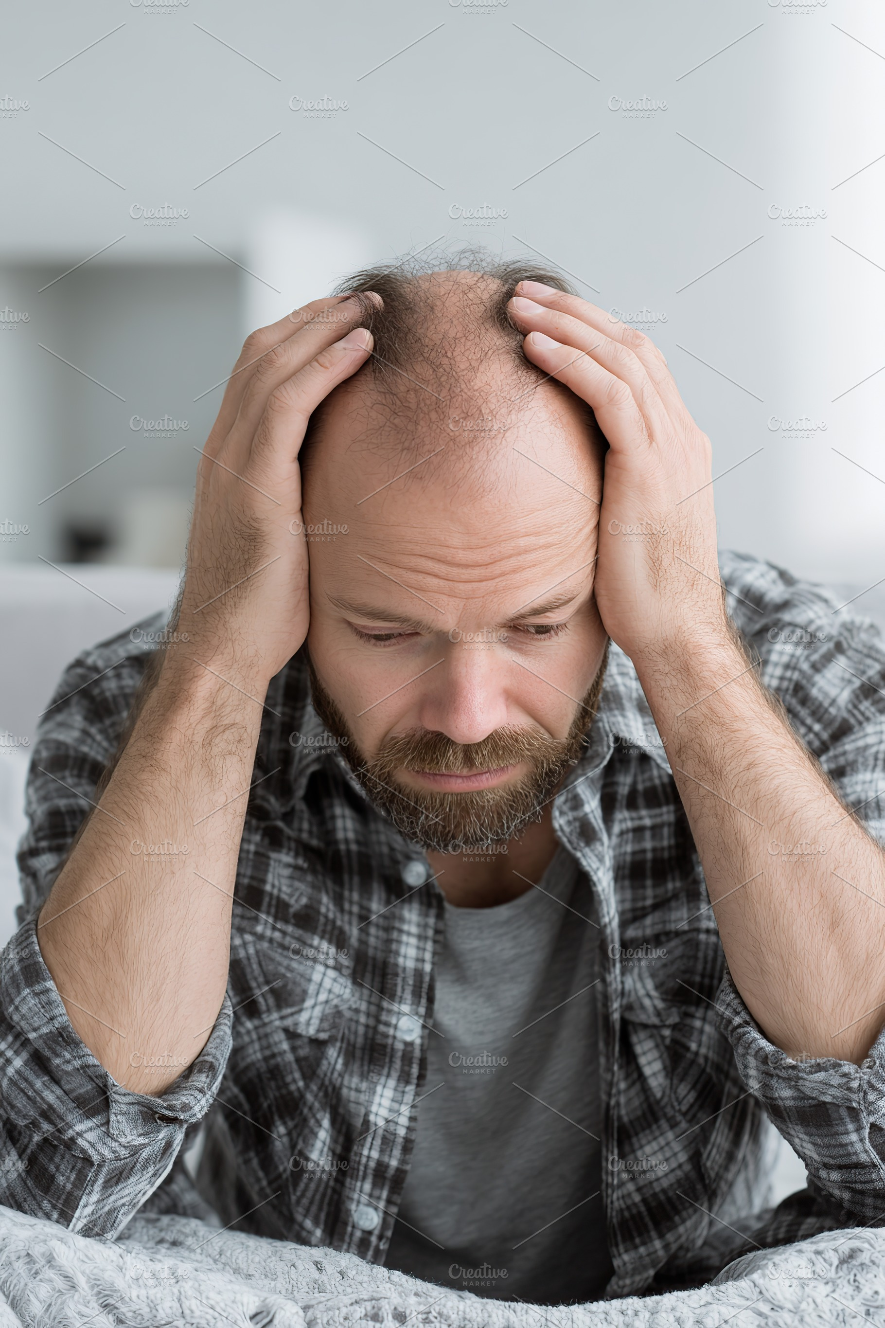 Man sitting on edge of bed with hands on head, displaying signs of stress or wo, a Person Photo by AlyaAnd