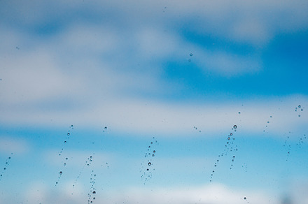 Raindrops on a window against the sky, an Abstract Photo by rubenchase