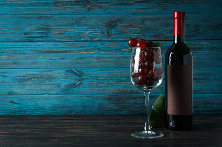 Bottle of wine, glass of grape and leaf on wooden table