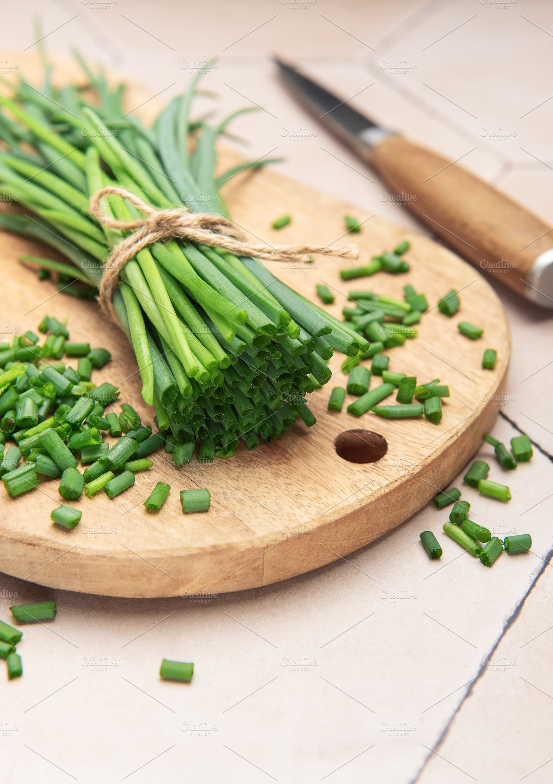 Freshly cut chives on wooden cutting board with knife, a Food & Drink Photo by Olena Rudo