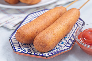 Two corn dogs on white blue plate, served with ketchup, horizontal, a Food & Drink Photo by iuliia_n