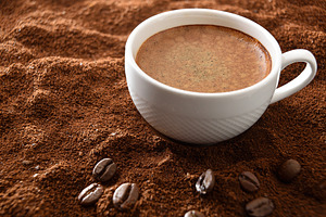 Cup of frothy coffee over ground with beans elevated view, a Food & Drink Photo by Davizro's Market
