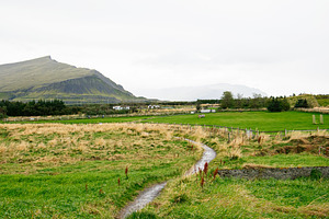 Scenic Icelandic countryside with grassy meadows and distant mountain under clo, a Nature Photo by AS photostudio