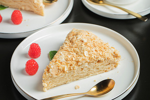 Sliced Napoleon cake on a white wooden table. Classic dessert, a Food & Drink Photo by Budarinphoto