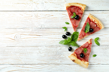 Slices of Salami pizza on white wooden background, a Food & Drink Photo by AtlasStudio PRO