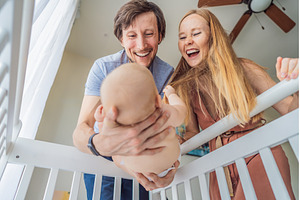 Mother and father lifting baby from, a Person Photo by Elizaveta Galitskaya